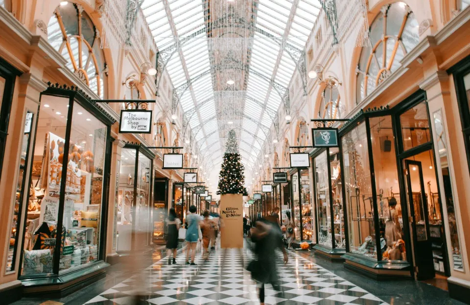 Galerie comercială luminoasă cu acoperiș de sticlă și un brad de Crăciun în centru