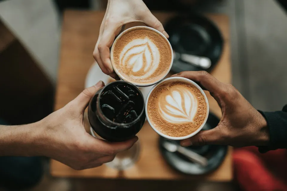 Prieteni care ciocnesc căni de cafea